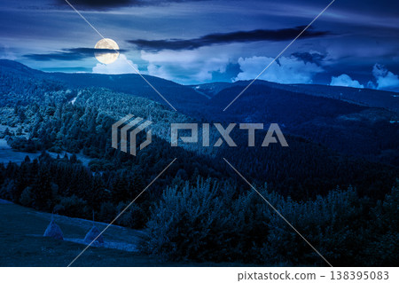mountain hay field at night. full moon over alpine countryside summer landscape with green valley behind the woods on the grassy slope. cloudy sky. mysterious highland background mountain hay field at night. full moon over alpine countryside summer landscape with green valley behind the woods on the grassy slope. cloudy sky. mysterious highland background 138395083