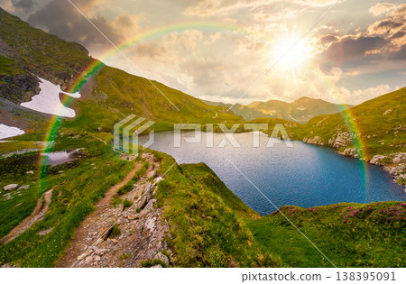 gorgeous summer sunset over capra lake. breathtaking evening view of transylvaia alps in romania. composite background image with rainbow in nature for hope and new beginning concept gorgeous summer sunset over capra lake. breathtaking evening view of transylvaia alps in romania. composite background image with rainbow in nature for hope and new beginning concept 138395091