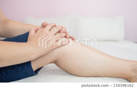 Woman with knee pain, she puts hands on her knee Woman with knee pain, she puts hands on her knee 138396162