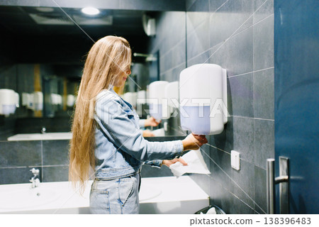Customer Using Paper Dispenser in Public Bathroom Customer Using Paper Dispenser in Public Bathroom 138396483