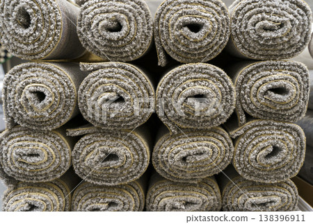 Industrial carpet production and storage with large rolls of textile flooring. Manufacturing process of various synthetic carpets in a warehouse or factory facility. Industrial carpet production and storage with large rolls of textile flooring. Manufacturing process of various synthetic carpets in a warehouse or factory facility. 138396911