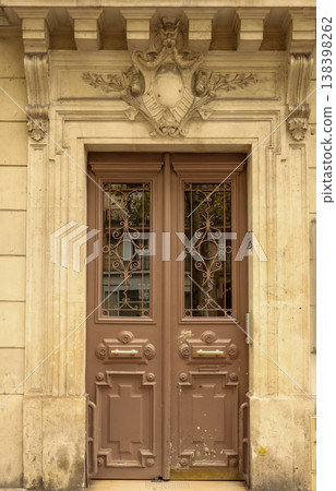 Ornate brown entrance door of a classic building with carved stone decorations in Paris, France Ornate brown entrance door of a classic building with carved stone decorations in Paris, France 138398262