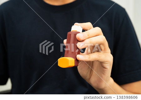 Asthma and chronic obstructive pulmonary disease COPD, Asian young man using metered dose inhaler MDI. Asthma and chronic obstructive pulmonary disease COPD, Asian young man using metered dose inhaler MDI. 138398606