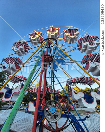 A bright Ferris wheel, towering against the blue sky A bright Ferris wheel, towering against the blue sky 138399480