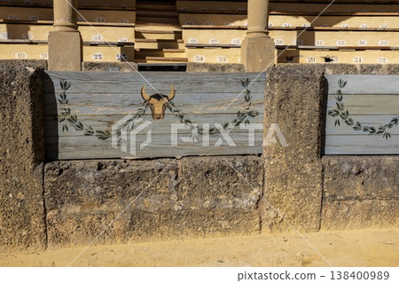 Plaza de Toros in Ronda shows bull paintings on wooden barriers and empty seating areas during the daytime 138400989