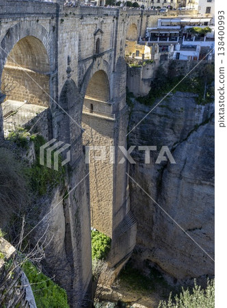 Bridges span a deep gorge in Ronda, Spain while buildings overlook the landscape on a sunny day 138400993