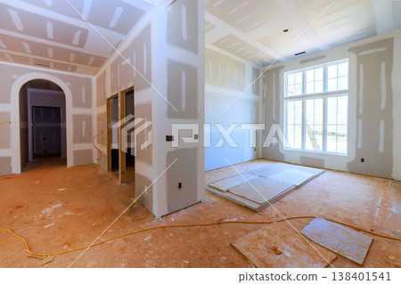 Workers are preparing new home interior with drywall, bare floors in room with large windows. Workers are preparing new home interior with drywall, bare floors in room with large windows. 138401541