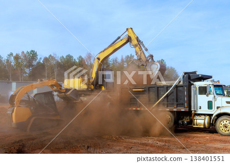 Heavy machinery removes dirt loads it into truck on construction site in rural area Heavy machinery removes dirt loads it into truck on construction site in rural area 138401551