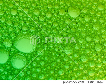 Close-up view of numerous green bubbles of various sizes on a green background with a gradient effect and shallow depth of field. 138401662