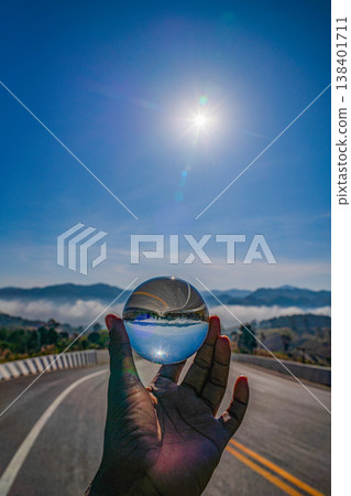 Hand Holding a Crystal Ball Reflecting a Winding Road in the Fog Hand Holding a Crystal Ball Reflecting a Winding Road in the Fog 138401711