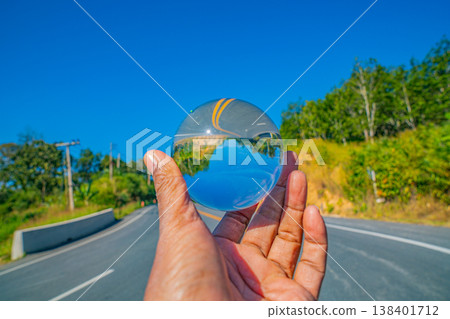 Hand Holding a Crystal Ball Showing a Journey Through a Mist Covered Valley Hand Holding a Crystal Ball Showing a Journey Through a Mist Covered Valley 138401712
