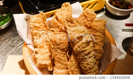close up of a basket of crispy deep fried Beancurd sheet rolls ( bean curd skin) served on parchment paper with dipping sauces, which are ingredient for Cantonese hot pot. close up of a basket of crispy deep fried Beancurd sheet rolls ( bean curd skin) served on parchment paper with dipping sauces, which are ingredient for Cantonese hot pot. 138402008