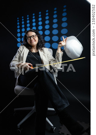Woman engineer smiling holding hard hat and measuring tape Woman engineer smiling holding hard hat and measuring tape 138402582