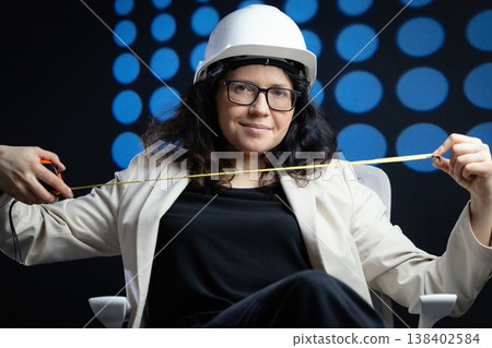Woman engineer wearing hard hat holding measuring tape Woman engineer wearing hard hat holding measuring tape 138402584