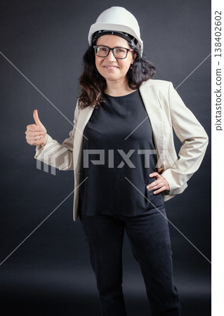 Woman engineer wearing hard hat giving thumbs up Woman engineer wearing hard hat giving thumbs up 138402602