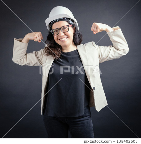 Confident woman architect builder flexing biceps Confident woman architect builder flexing biceps 138402603