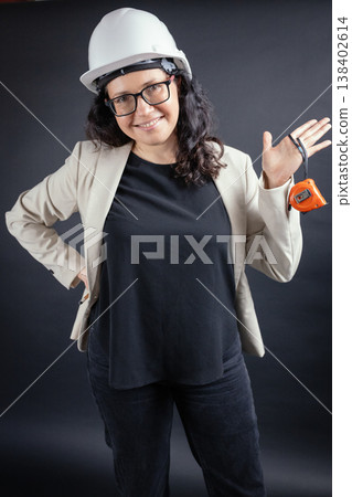 Smiling woman engineer holding measuring tape with hard hat Smiling woman engineer holding measuring tape with hard hat 138402614