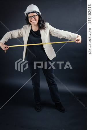 Female engineer wearing hard hat measuring space 138402618