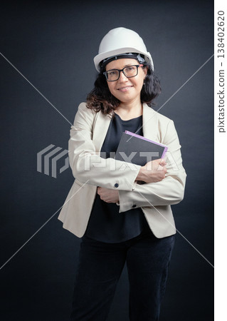 Woman engineer wearing hard hat holding documents 138402620