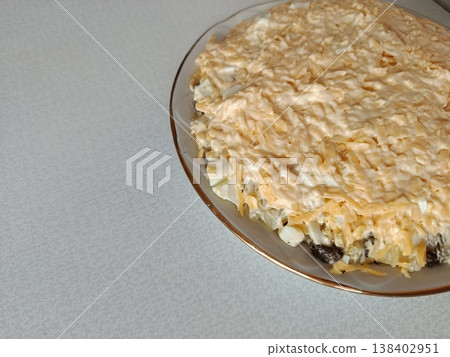 Layered salad presented on a white plate with a gold rim, showcasing a rich topping of grated cheese and creamy dressing, offering a traditional homemade dish Layered salad presented on a white plate with a gold rim, showcasing a rich topping of grated cheese and creamy dressing, offering a traditional homemade dish 138402951