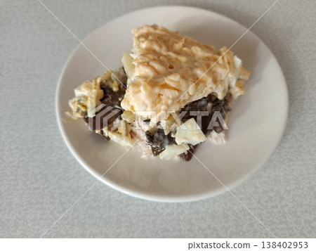 Layered salad with mushrooms, chicken, hard-boiled eggs, potatoes, and dressed with mayonnaise on a white plate, ready for consumption Layered salad with mushrooms, chicken, hard-boiled eggs, potatoes, and dressed with mayonnaise on a white plate, ready for consumption 138402953