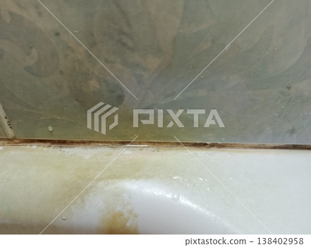 Close-up view of dirty bathtub caulk and tile showing extensive mold, mildew, grime, and water stains, emphasizing a need for unsanitary bathroom cleaning and repair 138402958