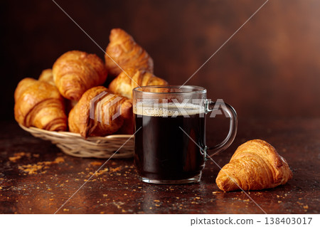 Black coffee and croissants on a brown background. Black coffee and croissants on a brown background. 138403017