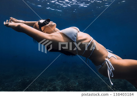 Woman free diving in white bikini underwater in clear blue ocean 138403184