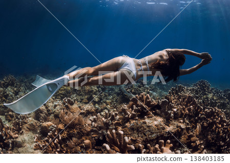 Female freediver swimming over coral reef with fins in tropical deep sea 138403185