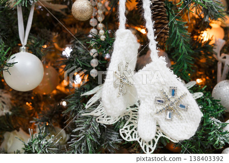 Winter holidays atmosphere background. Closeup of beautifully decorated fir tree with modern shiny baubles, beards, garland and small knitted mittens . Christmas and new year magic at home Winter holidays atmosphere background. Closeup of beautifully decorated fir tree with modern shiny baubles, beards, garland and small knitted mittens . Christmas and new year magic at home 138403392
