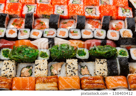 Sushi and rolls pattern background, japanese restaurant delivery top view. Salmon, unagi, california and other healthy meals Sushi and rolls pattern background, japanese restaurant delivery top view. Salmon, unagi, california and other healthy meals 138403412