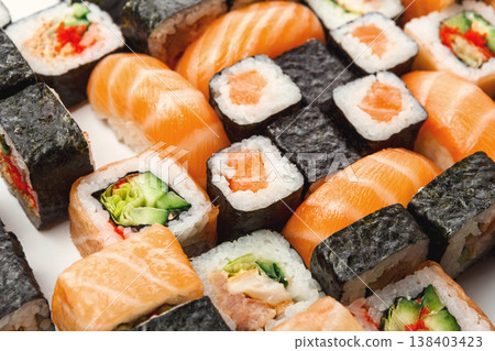 Sushi and rolls pattern background, japanese restaurant delivery. Salmon, unagi, california and other healthy seafood meals, closeup Sushi and rolls pattern background, japanese restaurant delivery. Salmon, unagi, california and other healthy seafood meals, closeup 138403423