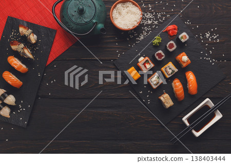 Sushi and rolls background, frame on black, top view. Colorful japanese restaurant food set with tea 138403444