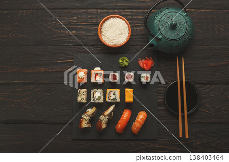 Colorful sushi and rolls platter in japanese restaurant, with teapot and chopsticks top view, copy space 138403464