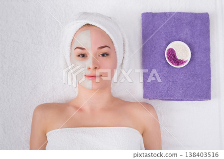 Face mask, spa beauty treatment. Woman applying facial clay mask at spa salon, skincare, top view, overhead Face mask, spa beauty treatment. Woman applying facial clay mask at spa salon, skincare, top view, overhead 138403516