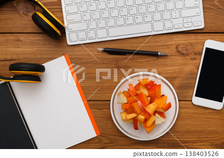Healthy business lunch at workplace. Top view flat lay of desktop - laptop, notepad and phone on wooden desk background with plate of fruit salad snack, nobody, objects Healthy business lunch at workplace. Top view flat lay of desktop - laptop, notepad and phone on wooden desk background with plate of fruit salad snack, nobody, objects 138403526