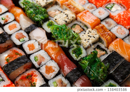 Sushi and rolls pattern background, japanese restaurant delivery closeup. Salmon, unagi, california and other healthy meals Sushi and rolls pattern background, japanese restaurant delivery closeup. Salmon, unagi, california and other healthy meals 138403586