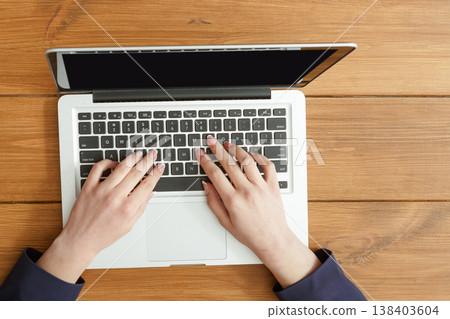 Female hands using laptop. Freelancer working with portable computer in coffee shop, top view, close up Female hands using laptop. Freelancer working with portable computer in coffee shop, top view, close up 138403604