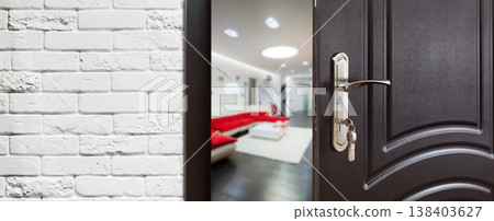 Half opened door to a living room. Door handle, door lock. Lounge door half open. Opening door. Welcome, privacy concept. Entrance to the room. Door at white brick wall, modern interior design. Half opened door to a living room. Door handle, door lock. Lounge door half open. Opening door. Welcome, privacy concept. Entrance to the room. Door at white brick wall, modern interior design. 138403627