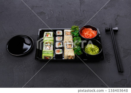 Japanese restaurant delivery, take away box pov, sushi maki and roll set. Chopsticks, ginger, soy sauce, wasabi. Meals at black background Japanese restaurant delivery, take away box pov, sushi maki and roll set. Chopsticks, ginger, soy sauce, wasabi. Meals at black background 138403648