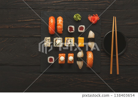 Japanese food restaurant, sushi and rolls on dark background. Set with chopsticks and soy sauce. Top view on black wood, copy space Japanese food restaurant, sushi and rolls on dark background. Set with chopsticks and soy sauce. Top view on black wood, copy space 138403654