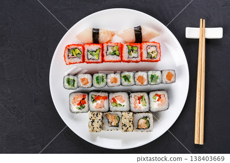 Japanese food restaurant, california salmon rolls and sushi platter. Set with chopsticks and soy sauce. Top view on black background Japanese food restaurant, california salmon rolls and sushi platter. Set with chopsticks and soy sauce. Top view on black background 138403669