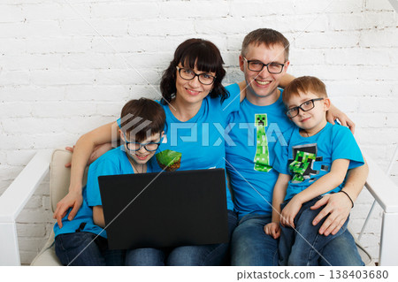 Happy family of four wearing eyeglasses. Parents and children, boys siblings in glasses with laptop computer. In white interior indoors. 138403680