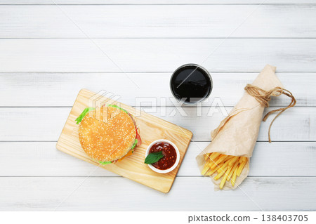 Burger, Chips and cola. Hamburger and french fries wrapped in brown wrapping paper. Fast food take away at white shabby chic wood. Hamburger with tomato sauce. Top view, flat lay with copyspace Burger, Chips and cola. Hamburger and french fries wrapped in brown wrapping paper. Fast food take away at white shabby chic wood. Hamburger with tomato sauce. Top view, flat lay with copyspace 138403705
