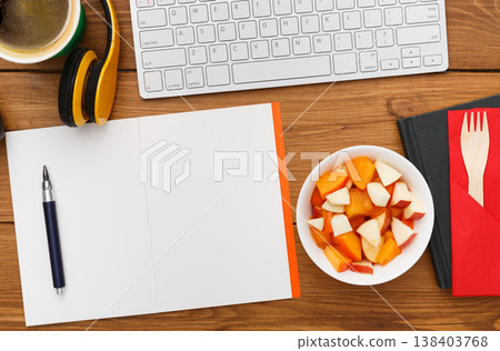 Healthy lunch at workplace. Top view with copy space, flat lay of desktop fruit snack in foil container on wooden desk background 138403768