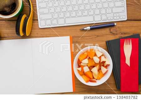 Healthy lunch at workplace. Top view with copy space, flat lay of desktop fruit snack in foil container on wooden desk background 138403782
