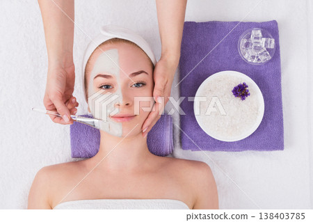 Face mask apply, spa beauty treatment, skincare. Woman getting facial care by beautician at spa salon, top view 138403785