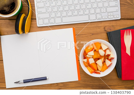 Healthy lunch at workplace. Top view with copy space, flat lay of desktop fruit snack in foil container on wooden desk background Healthy lunch at workplace. Top view with copy space, flat lay of desktop fruit snack in foil container on wooden desk background 138403790