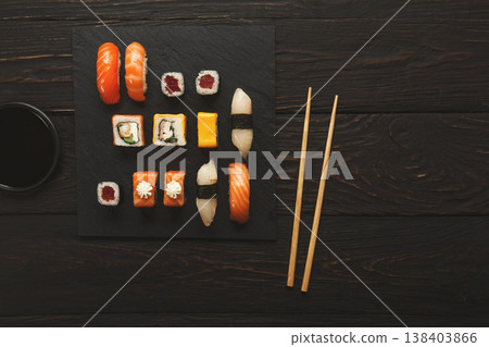 Japanese food restaurant, sushi and rolls on dark background. Set with chopsticks and soy sauce. Top view on black wood, copy space 138403866