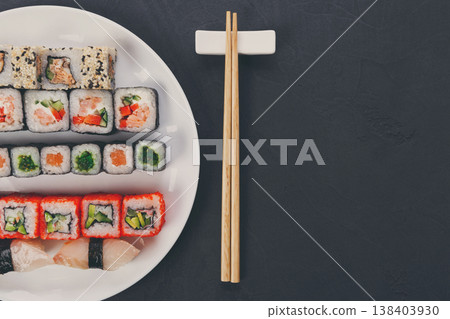 Japanese food restaurant, california salmon rolls and sushi platter. Set with chopsticks and soy sauce. Top view on black background Japanese food restaurant, california salmon rolls and sushi platter. Set with chopsticks and soy sauce. Top view on black background 138403930